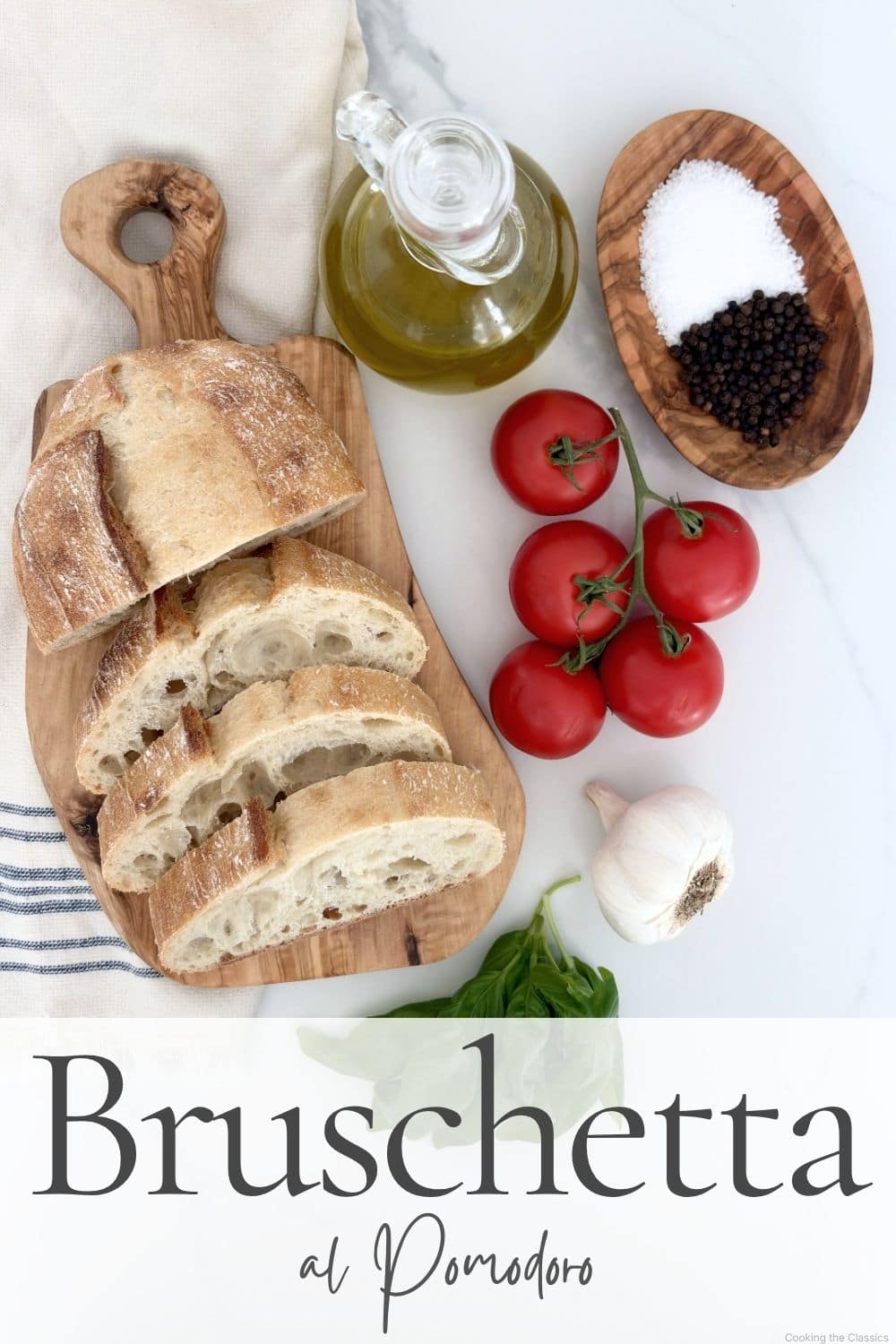 Flat lay of bruschetta al pomodoro ingredients including tomatoes, basil, olive oil, garlic, and bread on a marble surface.