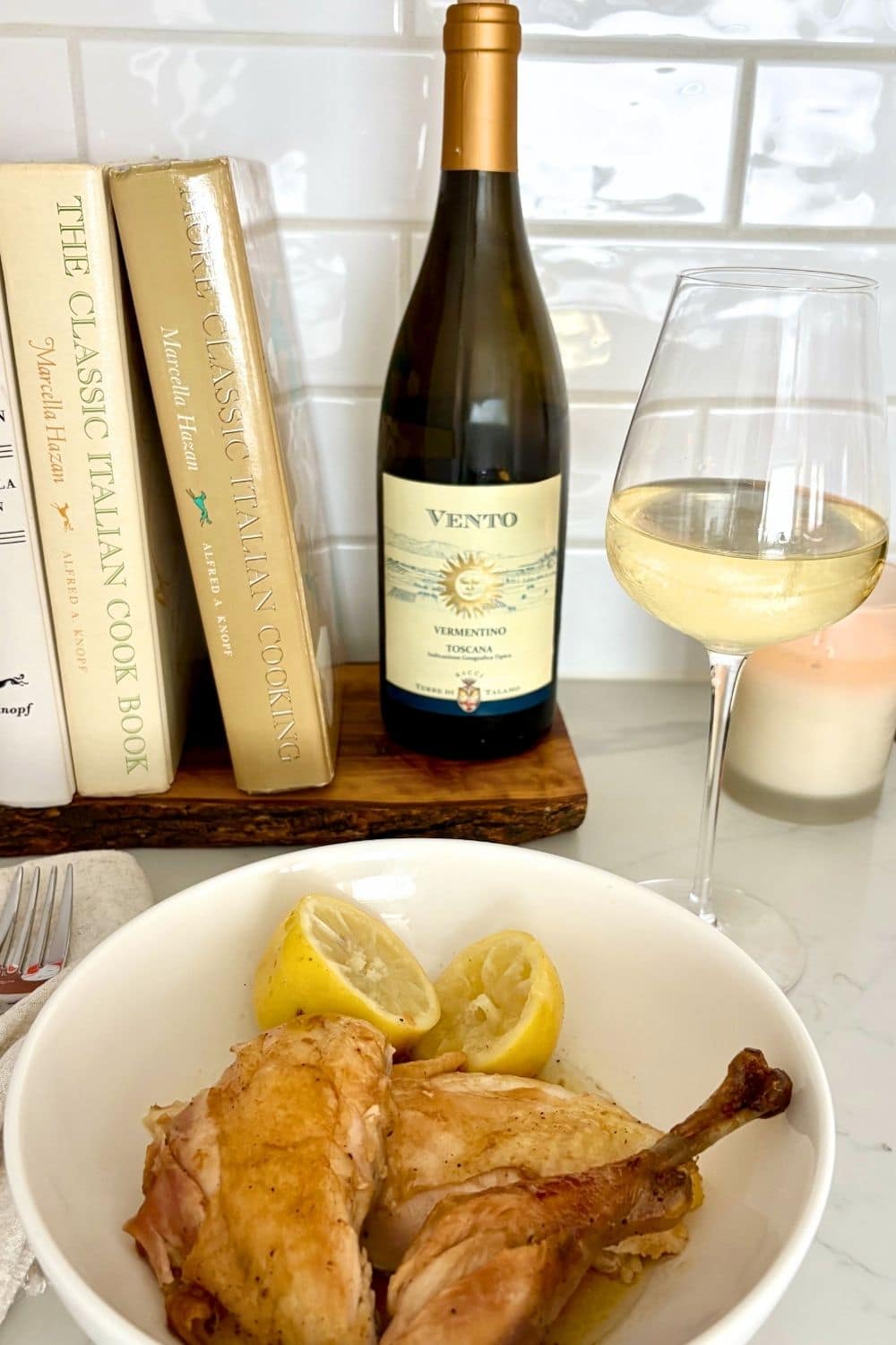 Roast chicken with lemons served on a plate with a glass of Vermentino wine.