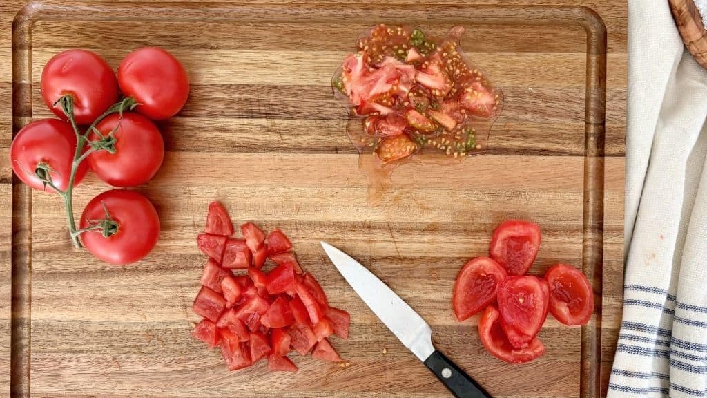 Cutting tomatoes on a cutting board for bruschetta al pomodoro preparation.