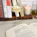 classic cookbooks next to stove with glass of wine and a book open to a recipe