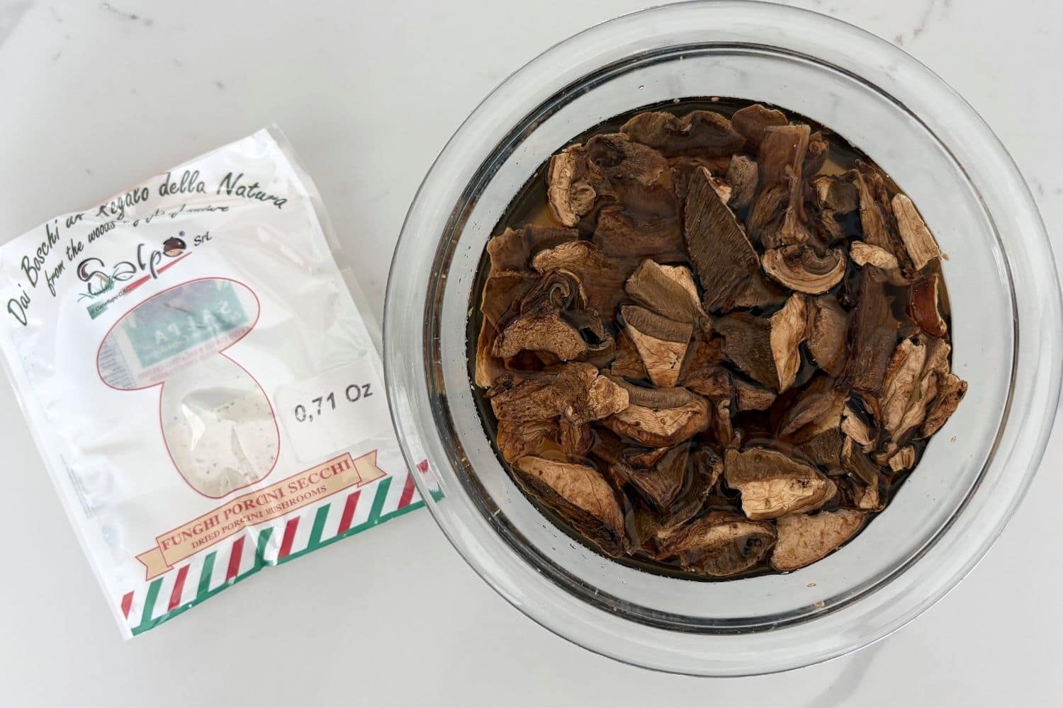 Dried porcini mushrooms soaking in water with package shown before reconstitution