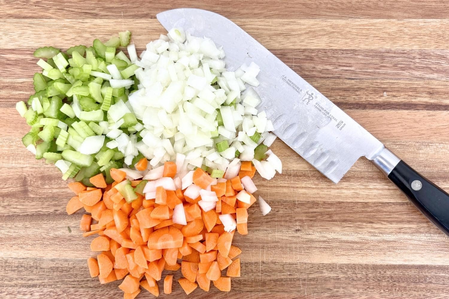 Soffritto pile of onions, carrots, and celery with a knife