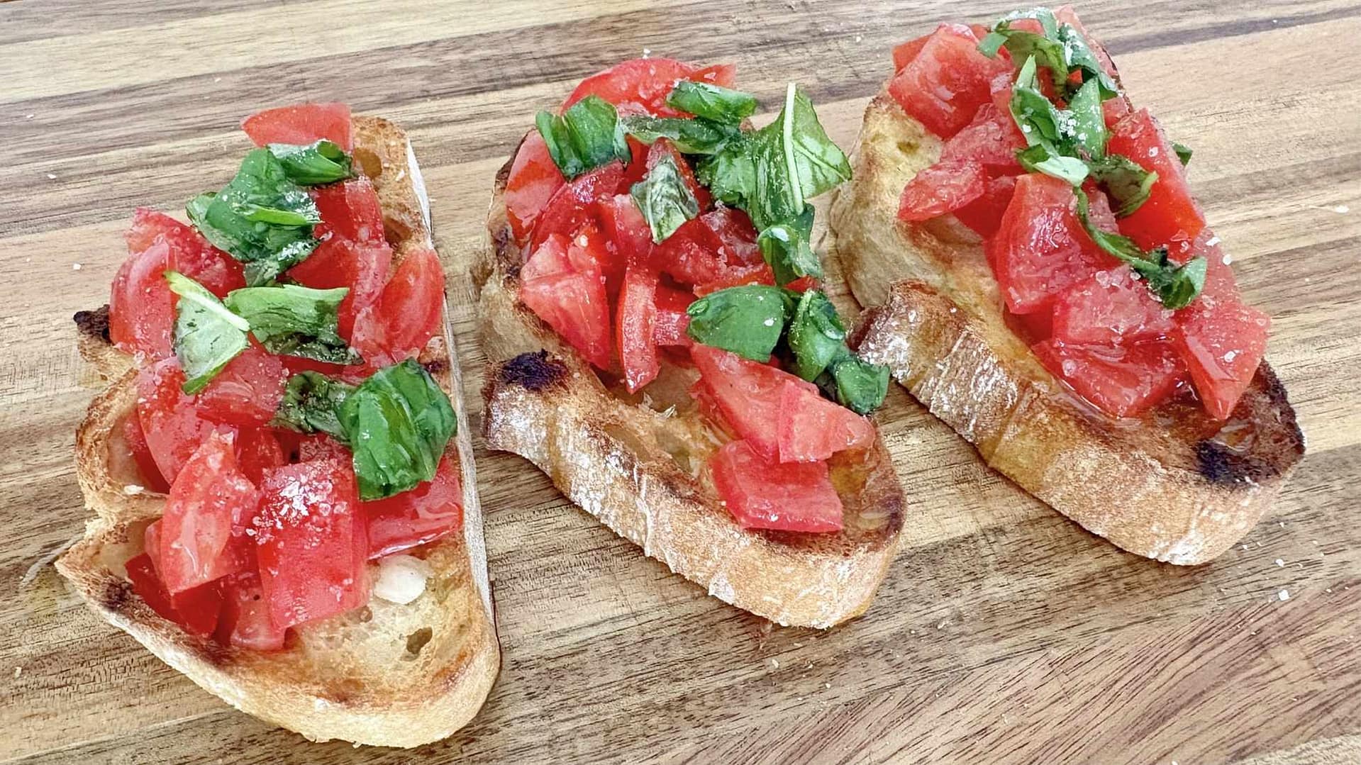 Close up texture of bruschetta al pomodoro with fresh tomatoes, basil, and olive oil on toasted bread.