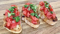 Close up texture of bruschetta al pomodoro with fresh tomatoes, basil, and olive oil on toasted bread.