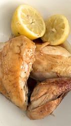 Roast chicken with lemons plated with the lemons as garnish.