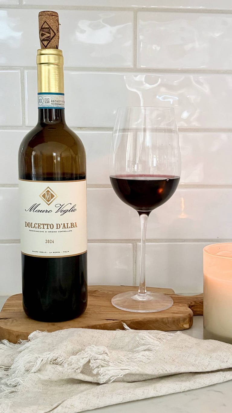 Bottle of Dolcetto red wine with a glass of red wine on a wooden board
